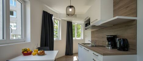 Una cocina moderna con encimera blanca, armarios de madera y una cafetera.