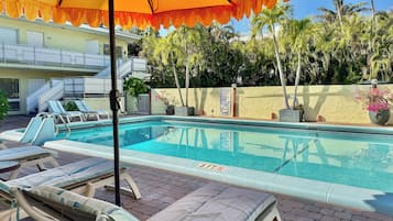 Una piscina al aire libre, sombrillas, sillones reclinables de piscina