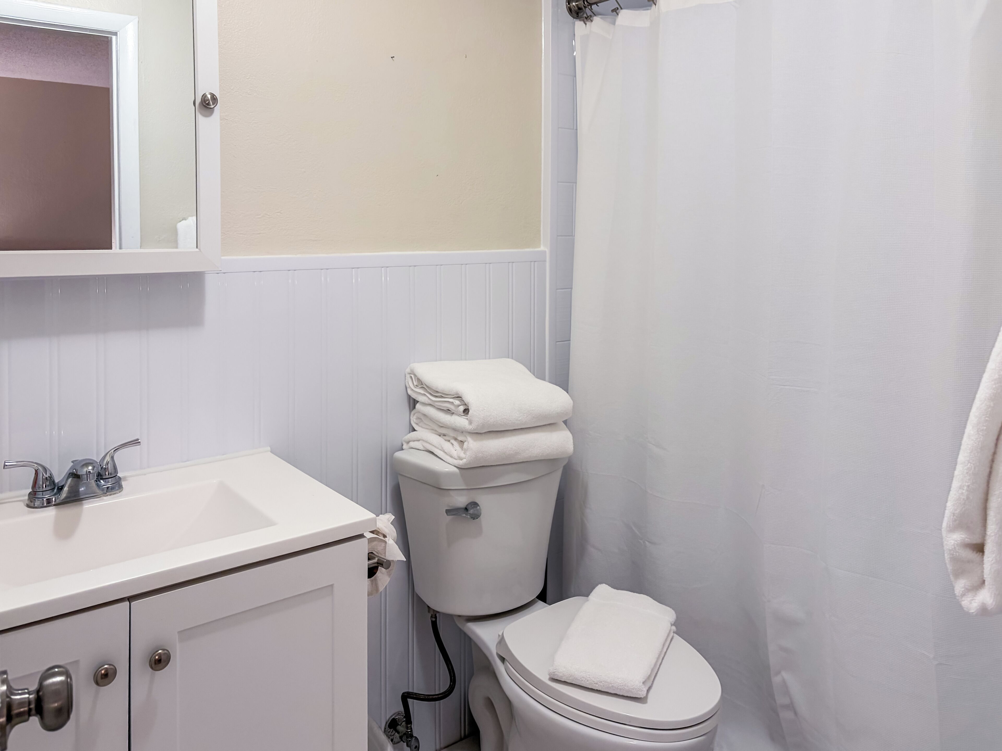A bathroom with a white sink, toilet, and shower curtain.