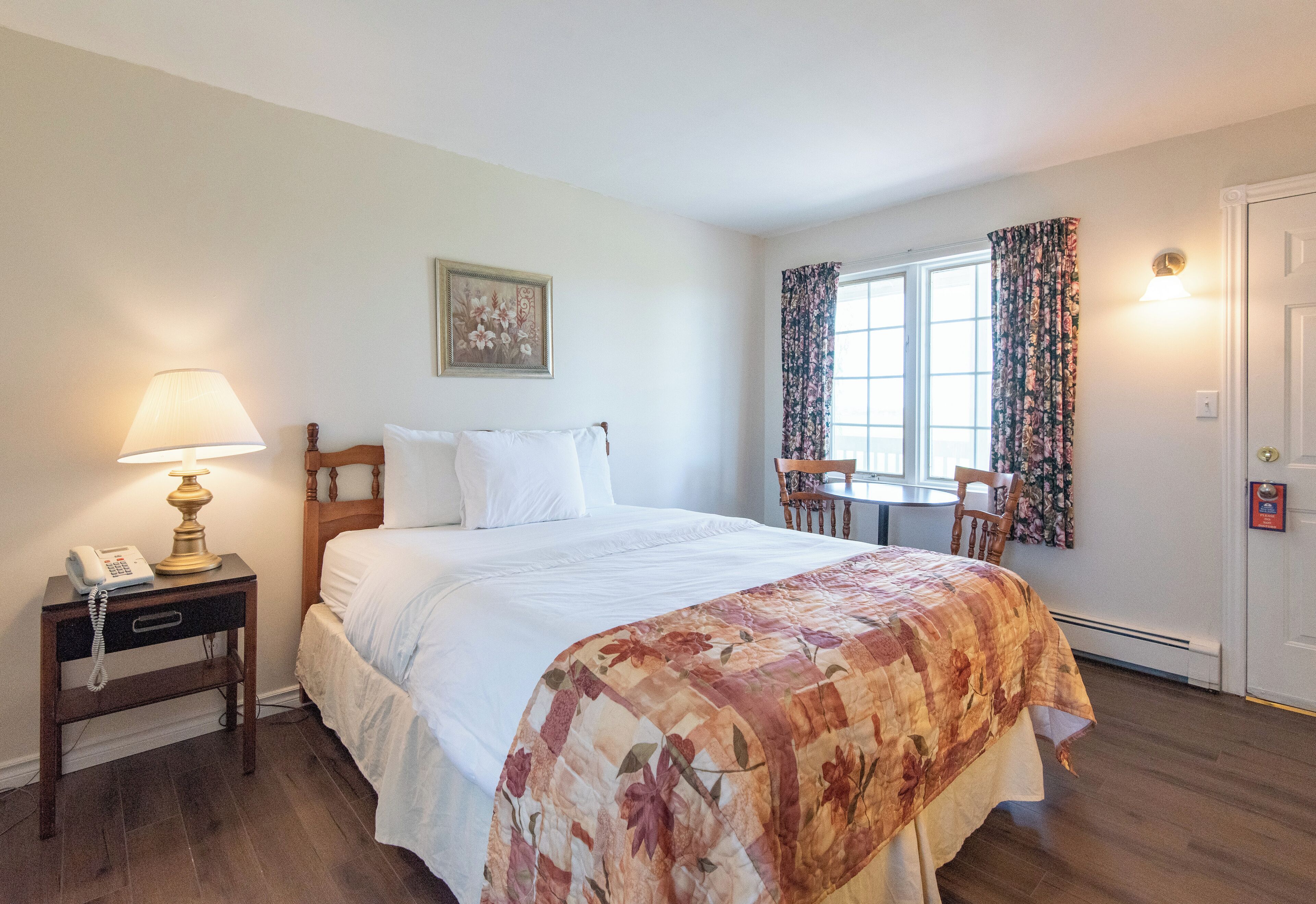 A neatly arranged bedroom with a bed, bedside lamp, and a small table with a telephone.