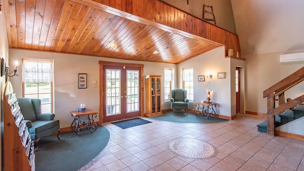 A spacious room with a high wooden ceiling, a fireplace, and a staircase leading to an upper level. - Canadas Best Value Inn & Suites Summerside (North Bedeque)
