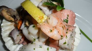 A plate of seafood including shrimp, scallops, and mussels, garnished with herbs.