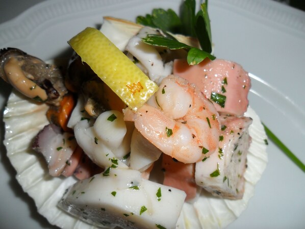 A plate of seafood including shrimp, scallops, and mussels, garnished with herbs.