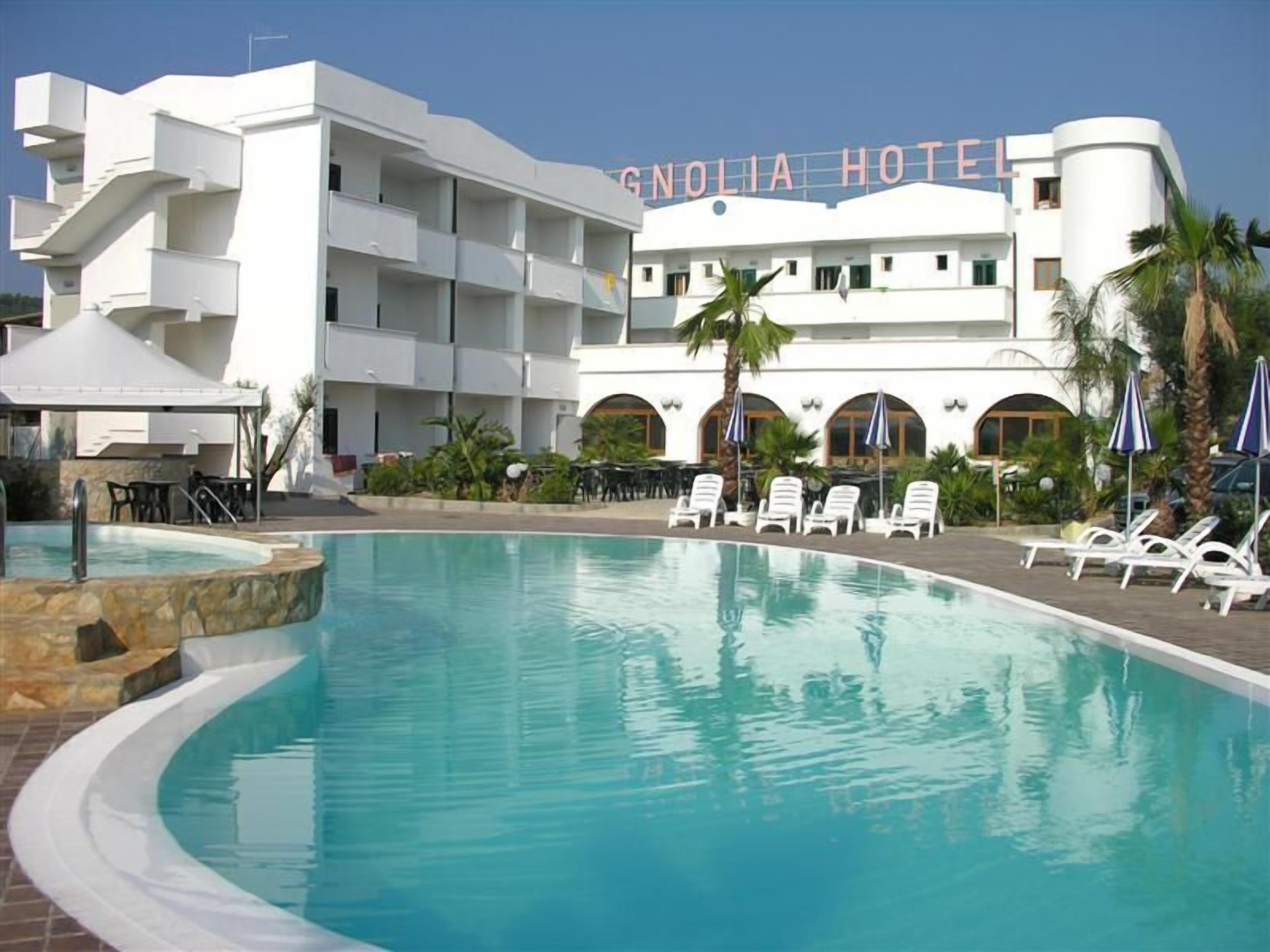 A hotel with a pool, lounge chairs, and palm trees.