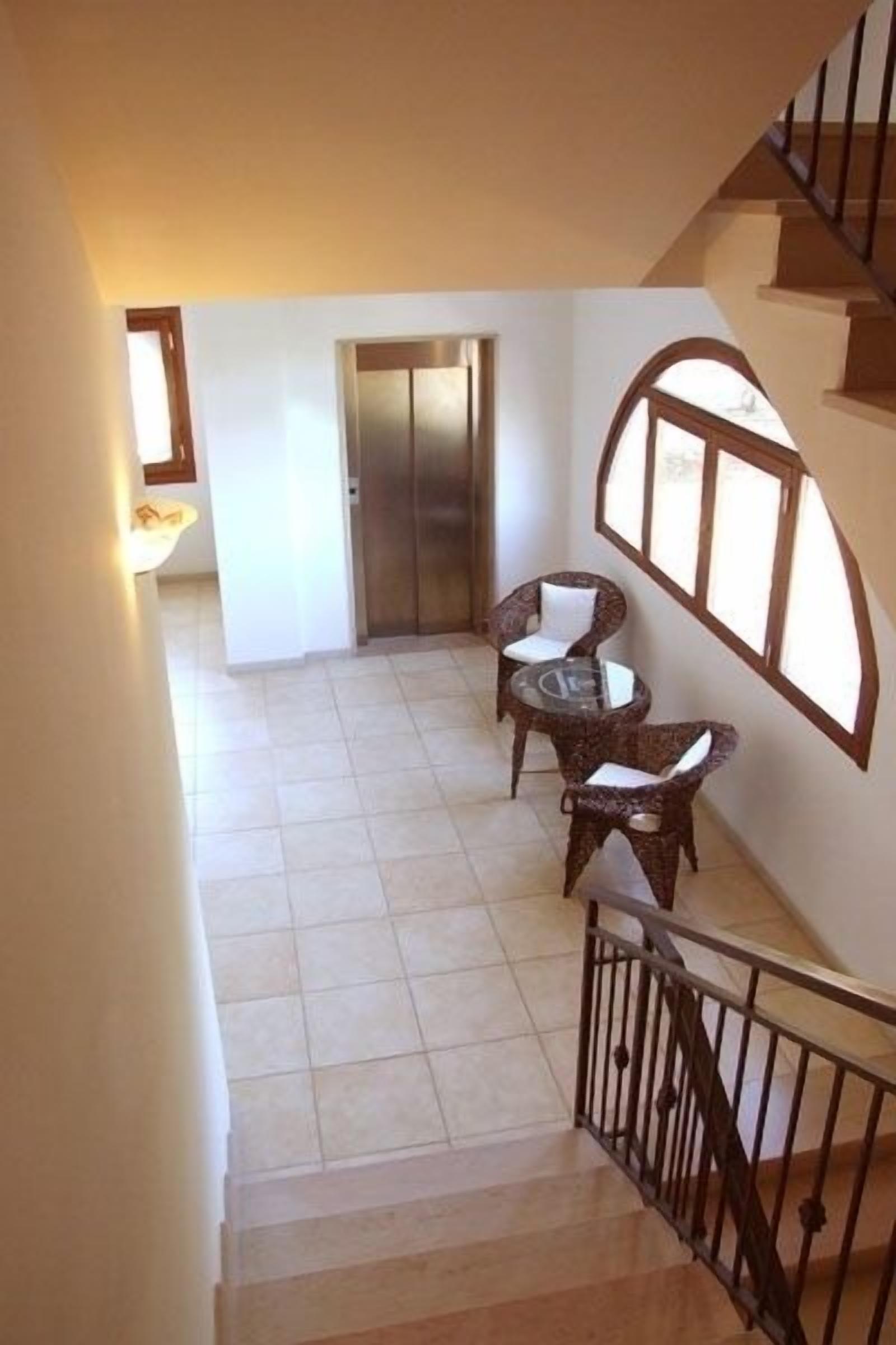 Una escalera conduce a una plataforma con dos sillones de mimbre y una pequeña mesa.
