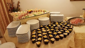 Une table de buffet garnie de différents plats et sur laquelle sont empilées des assiettes.