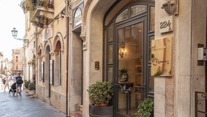 Un edificio histórico con un amplio acceso en arco, plantas en macetas y un cartel que indica que es un hotel.