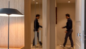Un pasillo moderno con una pared de acento de madera, una lámpara de pie y una persona caminando con una tableta.
