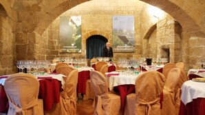 A banquet hall with stone arches, round tables set with wine glasses, and banners on the walls. - Grand Hotel Italia (Orvieto)