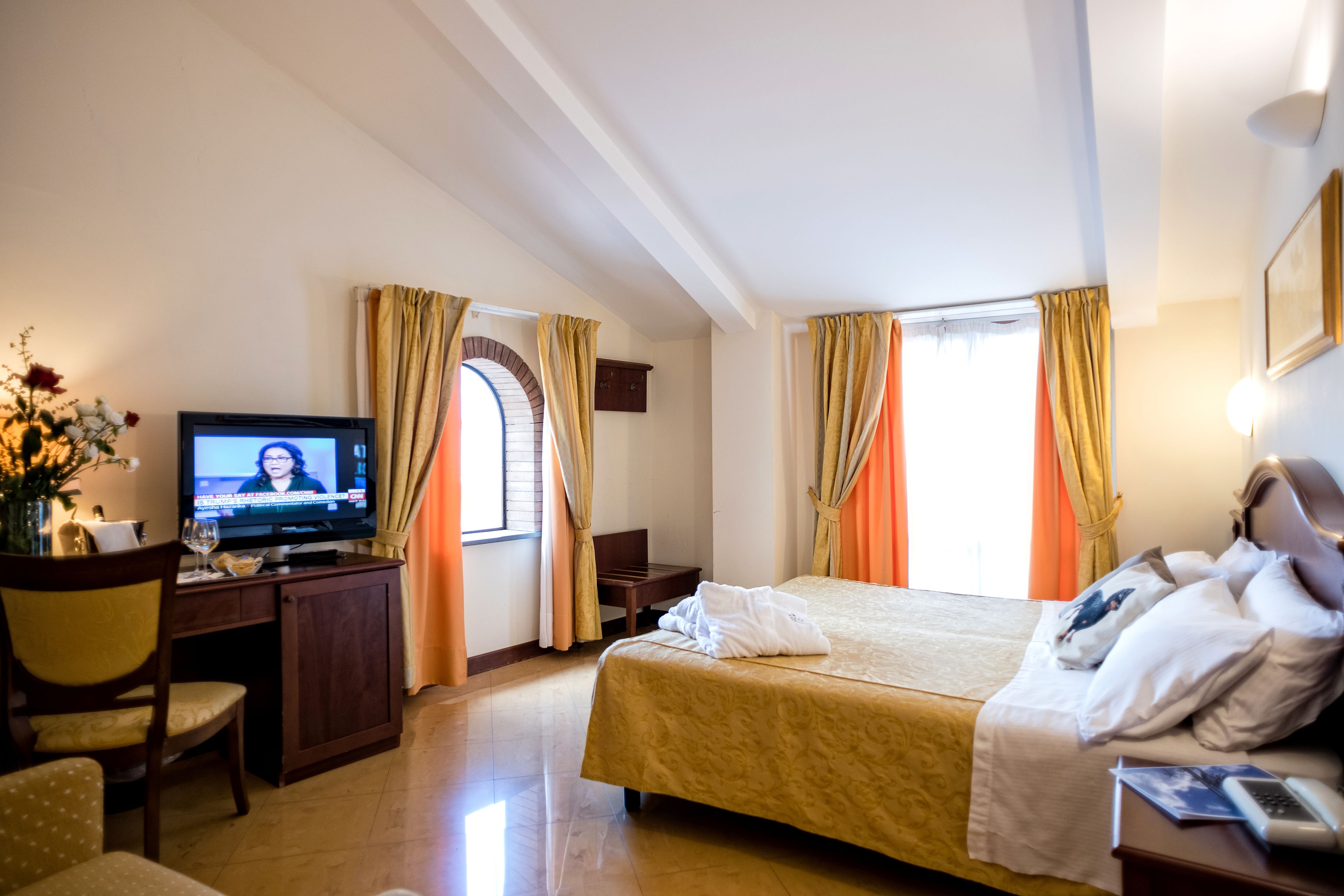Habitació d'hotel amb un llit, una taula de nit amb televisió i una cadira.