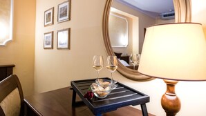 A hotel room with a dining table, two wine glasses, a bowl of fruit, and a lamp. - Grand Hotel Italia (Orvieto)