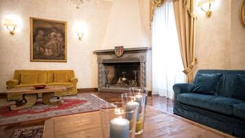 A living room with a fireplace, two sofas, a coffee table, and a chandelier.