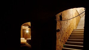 A dimly lit staircase in a stone-walled corridor with a light at the top. - Grand Hotel Italia (Orvieto)