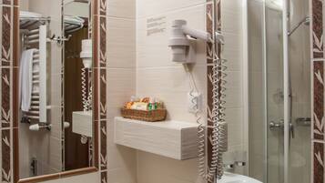 Un baño con lavabo blanco, espejo, secador de pelo y cabina de ducha de cristal.