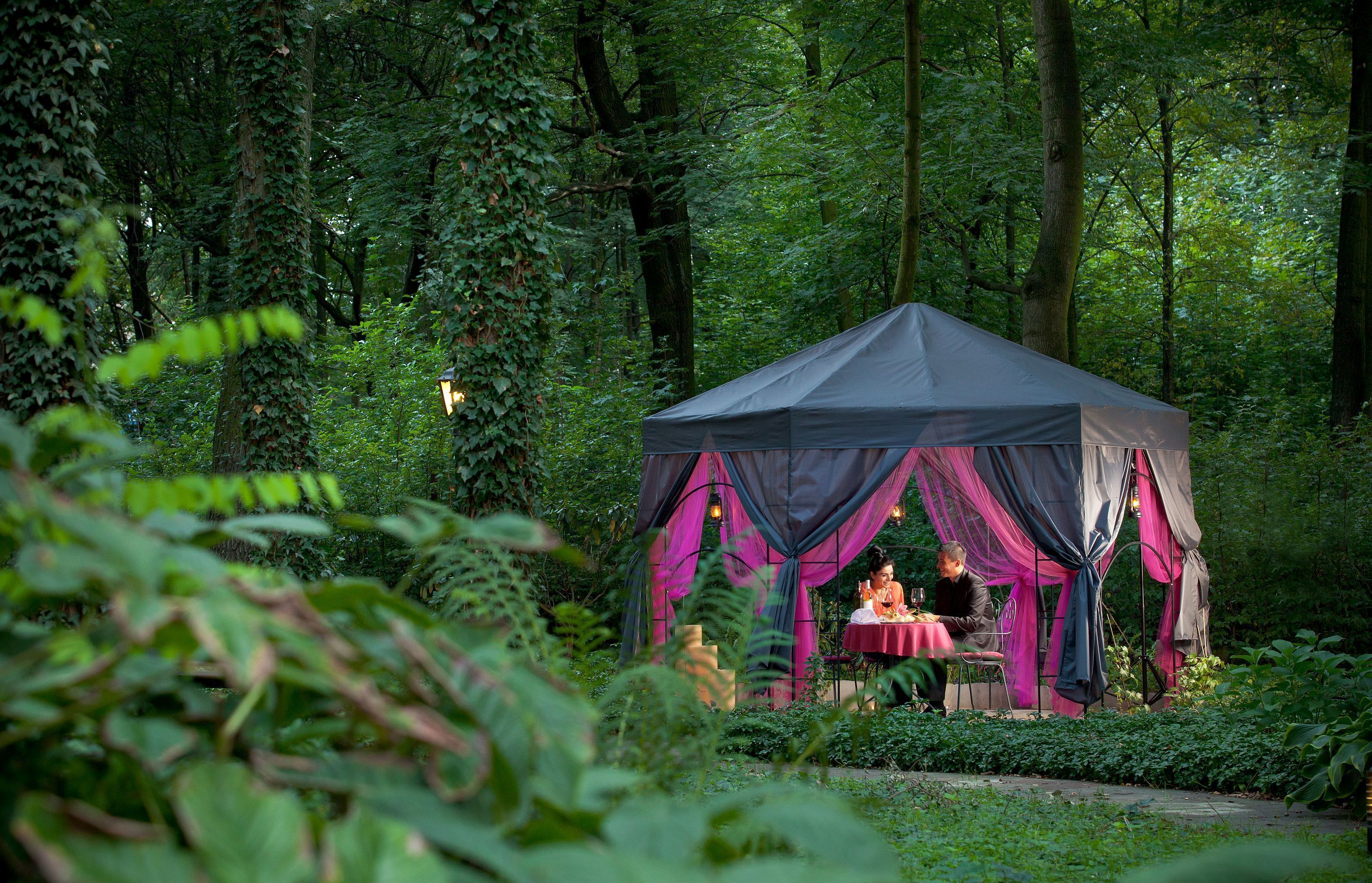 A tented outdoor dining area surrounded by lush greenery.