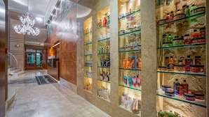 Een hotel lobby met een kroonluchter, glazen vitrines met toiletartikelen en een marmeren vloer.