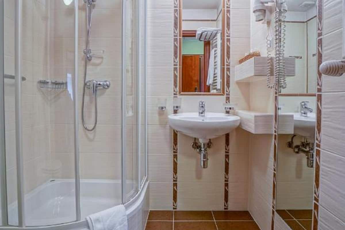 Un baño con ducha de vidrio, lavamanos blanco y espejo.