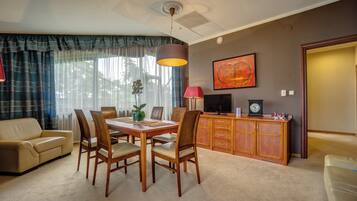 A dining area with a table, chairs, a television, and a clock on a wooden cabinet.