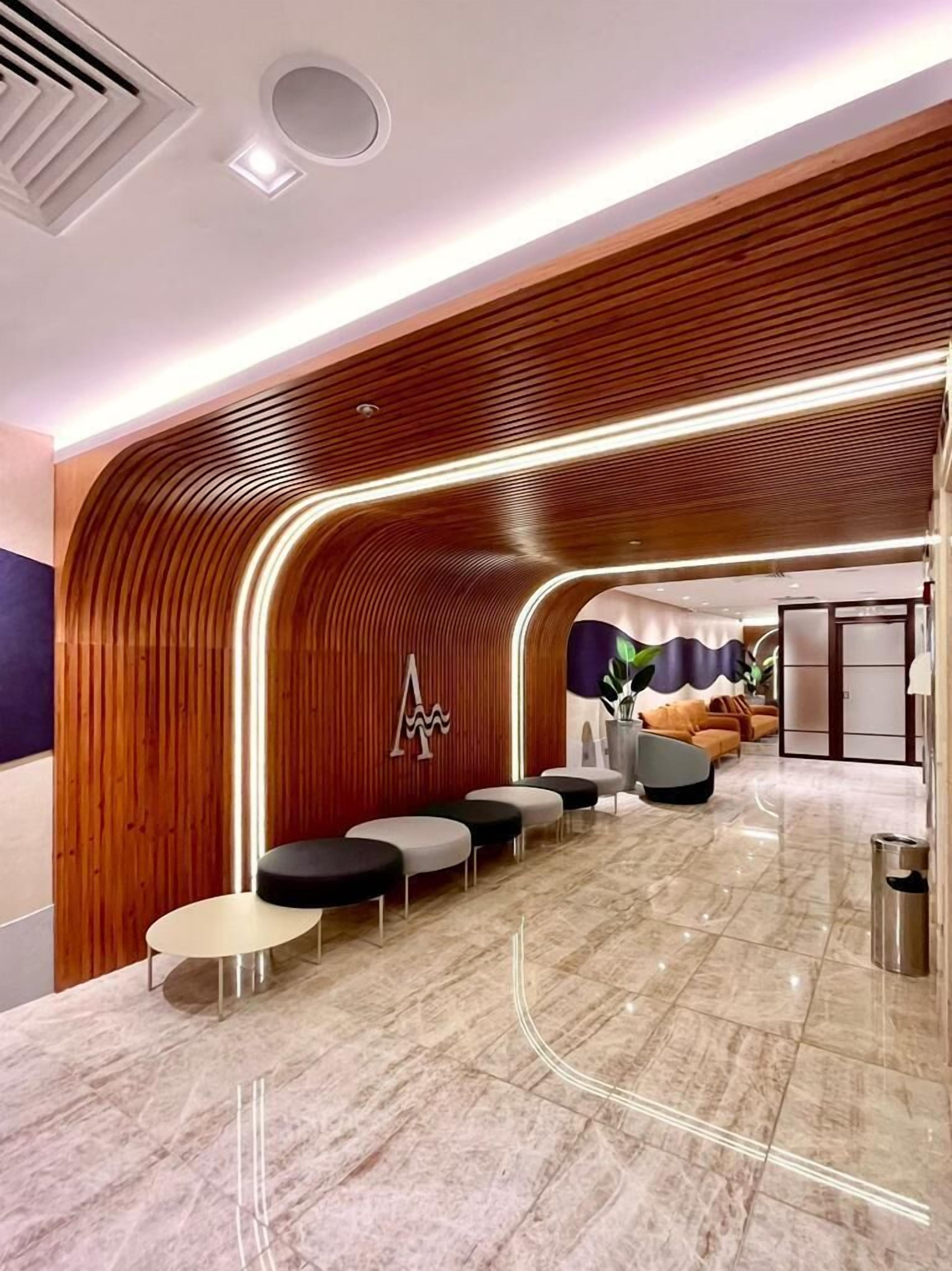 A modern lobby with a curved wooden wall, seating area, and a reception desk.