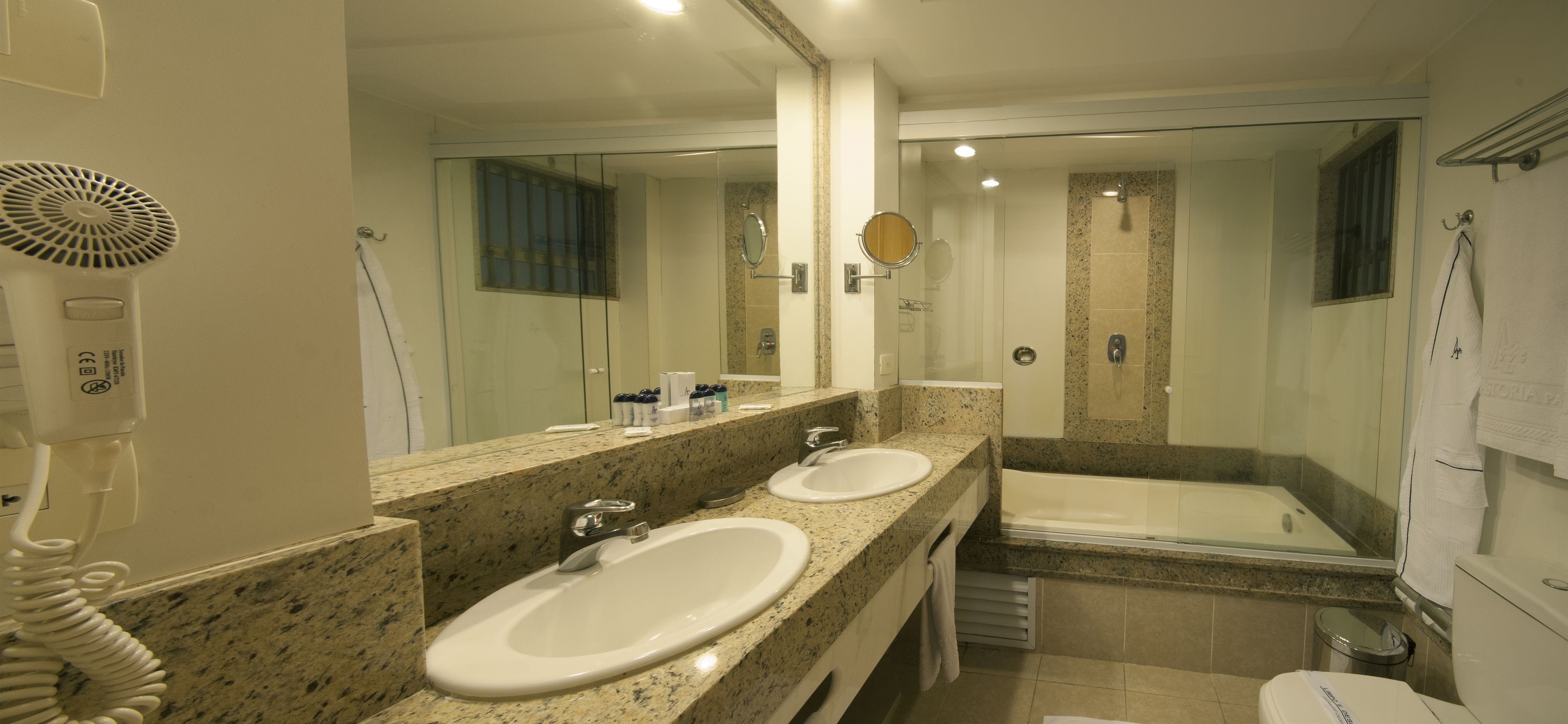 Une salle de bain avec deux lavabos, un grand miroir, une douche et des toilettes.