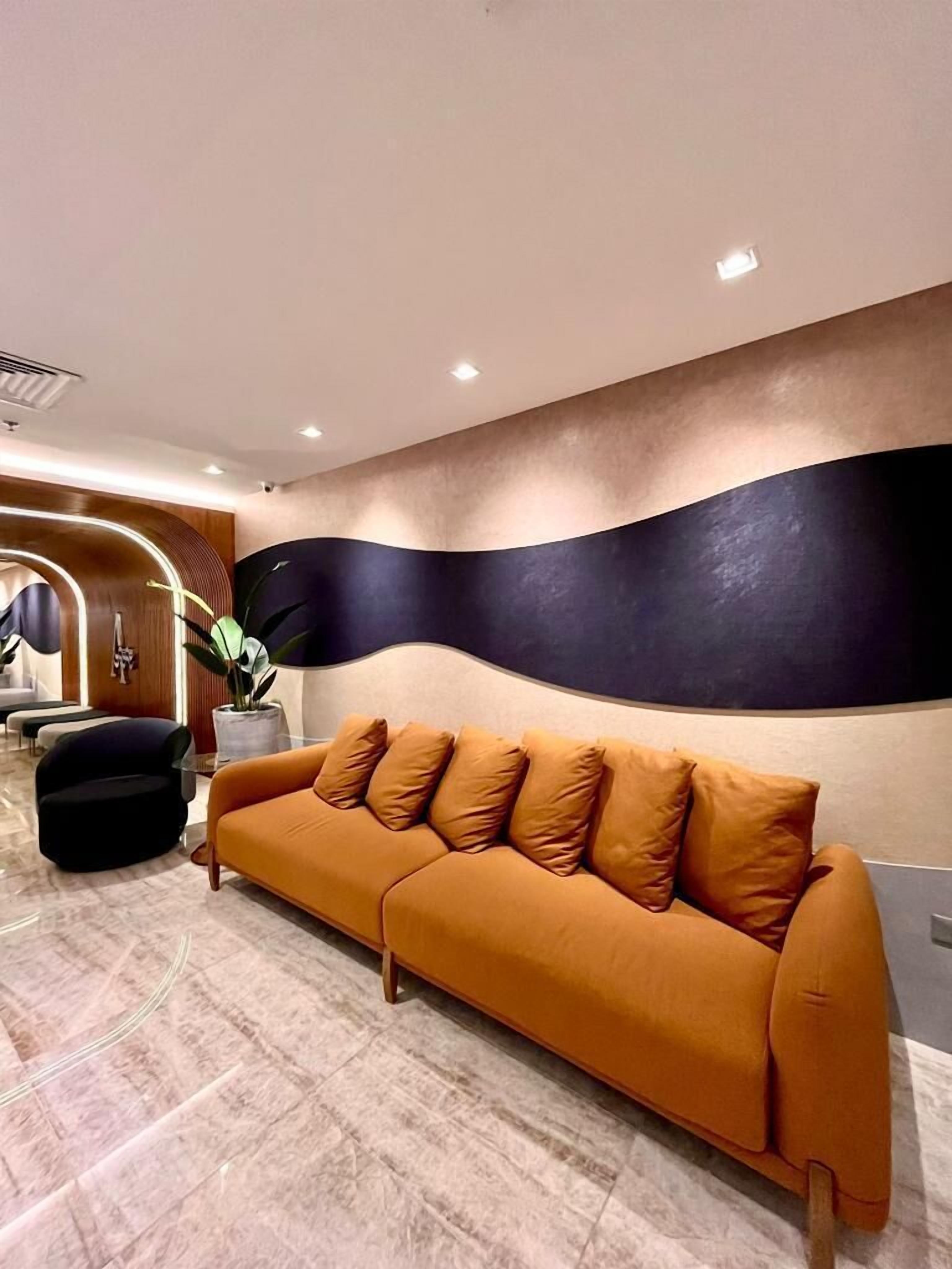 A modern lobby with a curved wall, a sofa, and a potted plant.