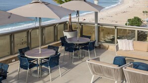 Una terraza con mesas al aire libre, sombrillas y vistas a la playa.