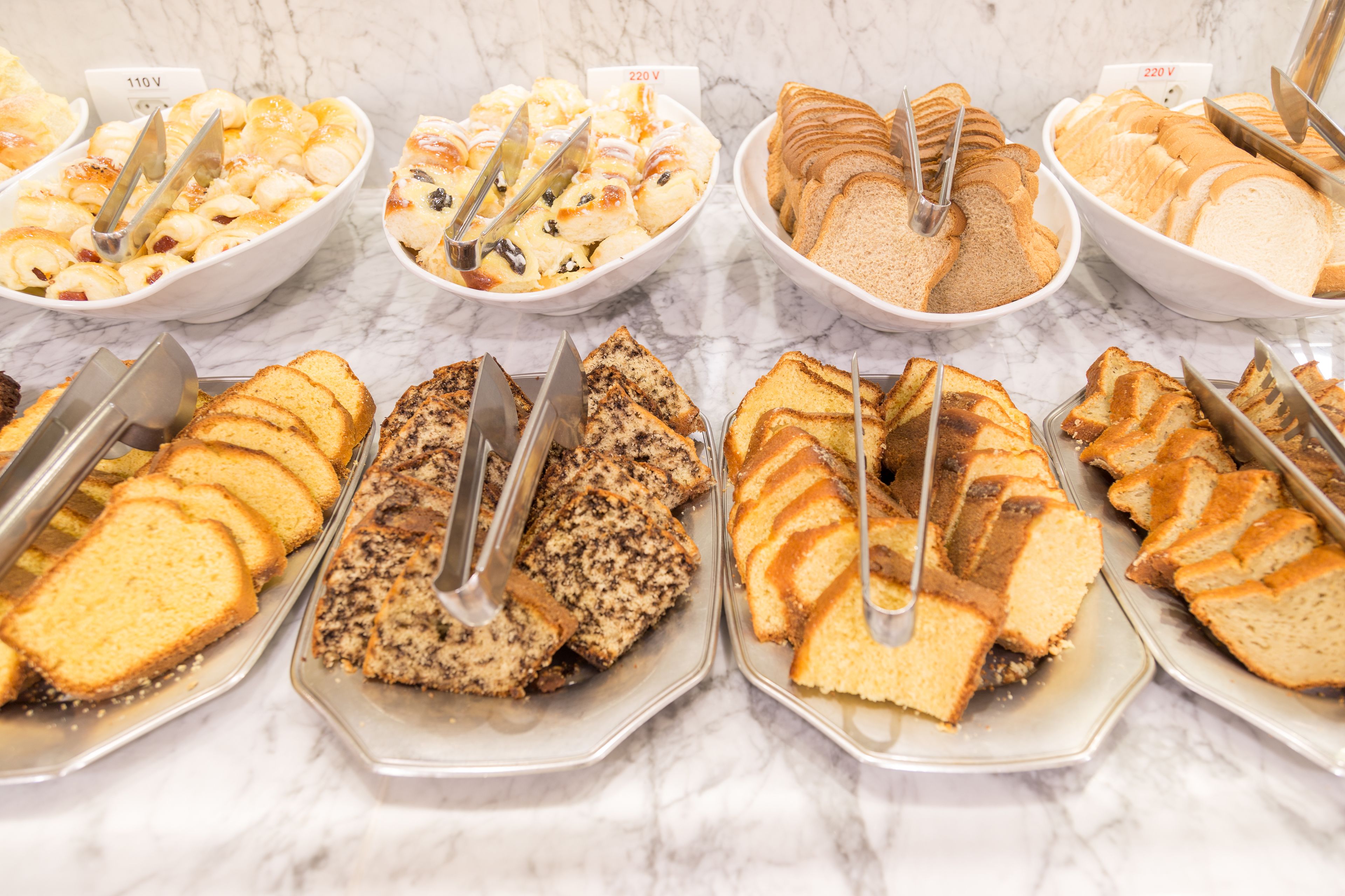 A buffet with various types of bread and pastries.