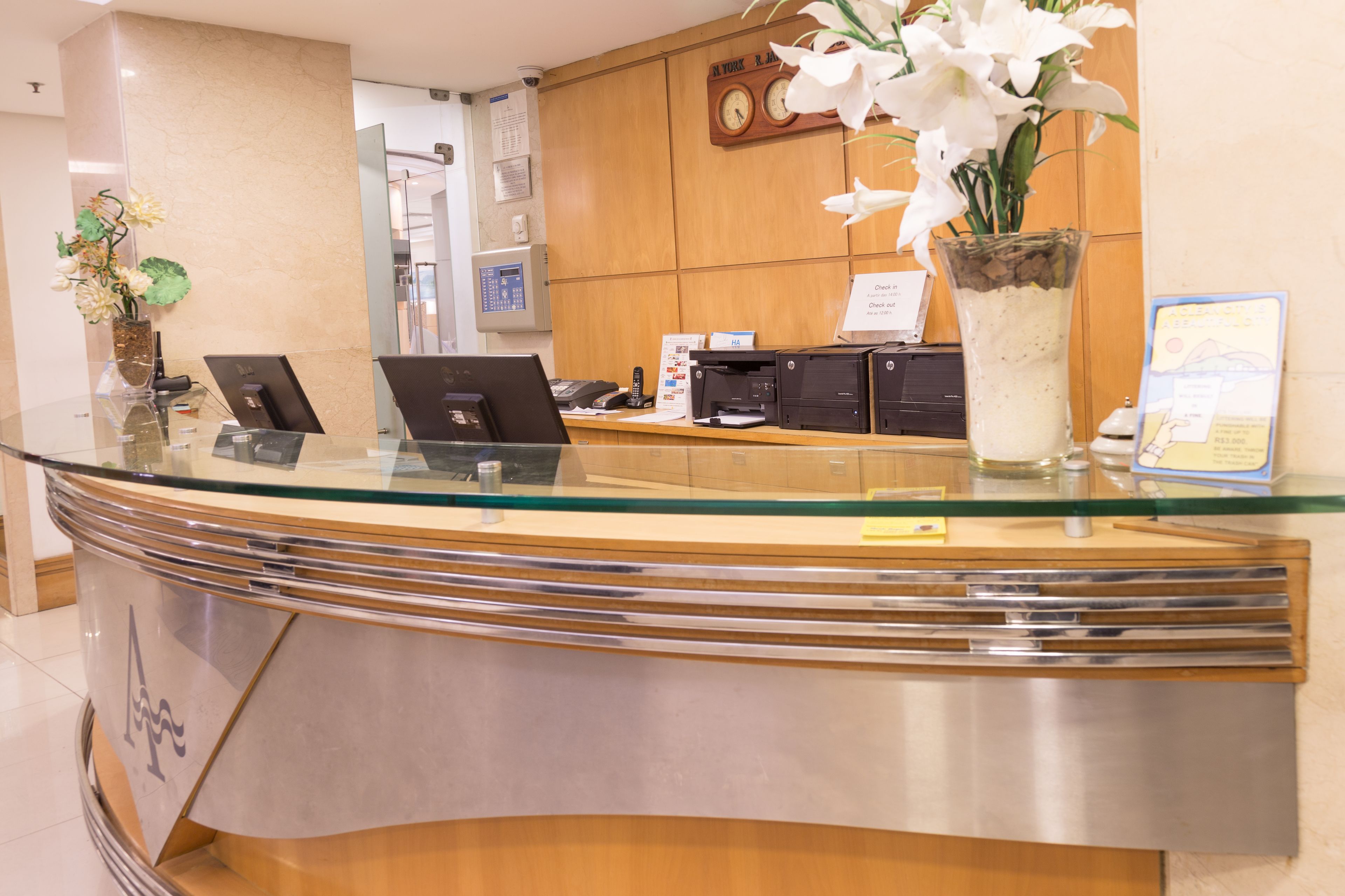 A reception desk with glass top, a clock, and a vase of white flowers.