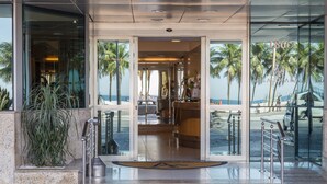 La entrada del Hotel Astoria Palace con vista a la playa y palmeras.