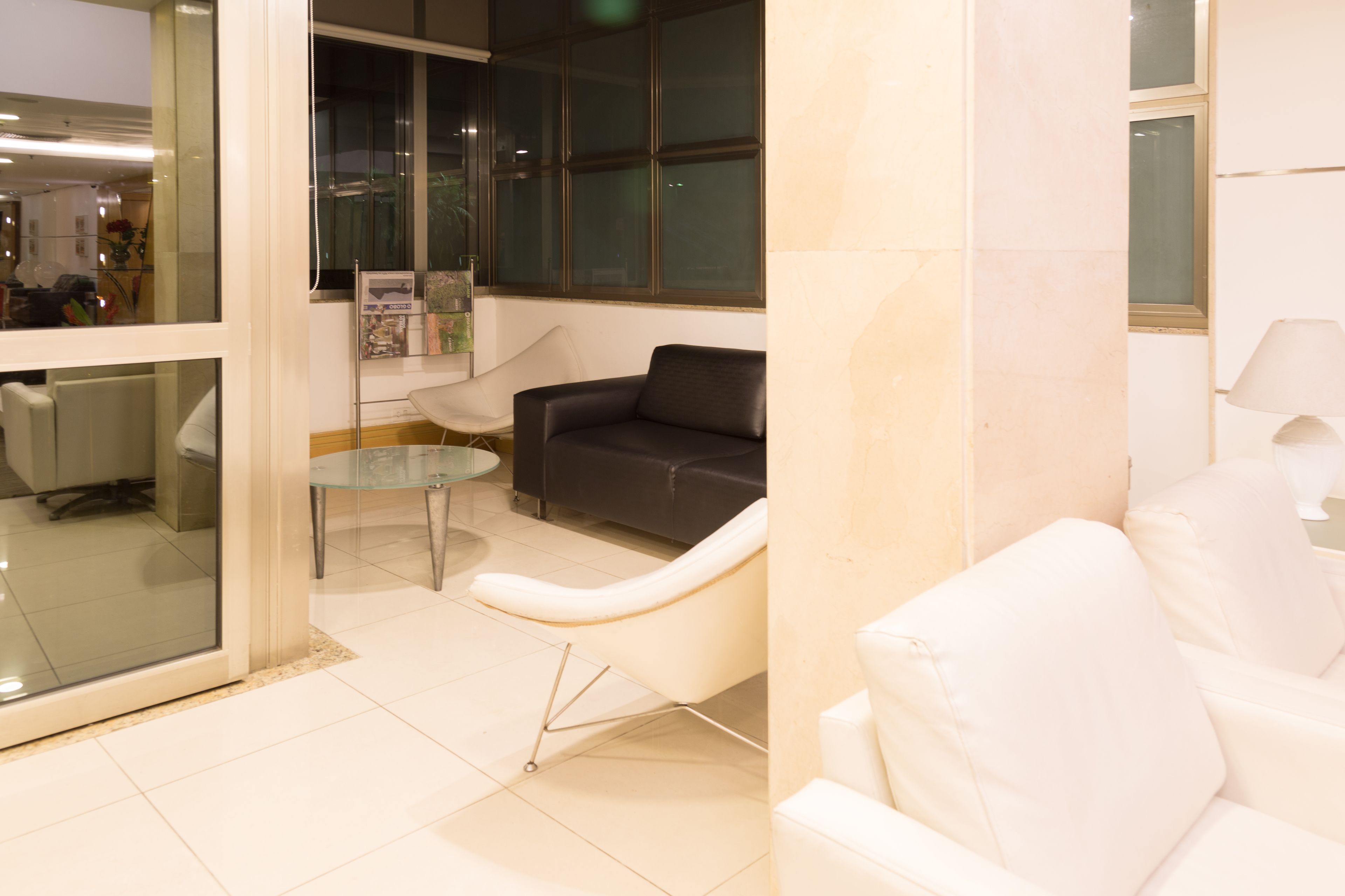 A modern waiting area with a glass partition, a glass table, and two sofas.