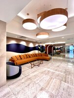 A modern lobby with a curved orange sofa, a coffee table, and a large wall with a wave-like design.