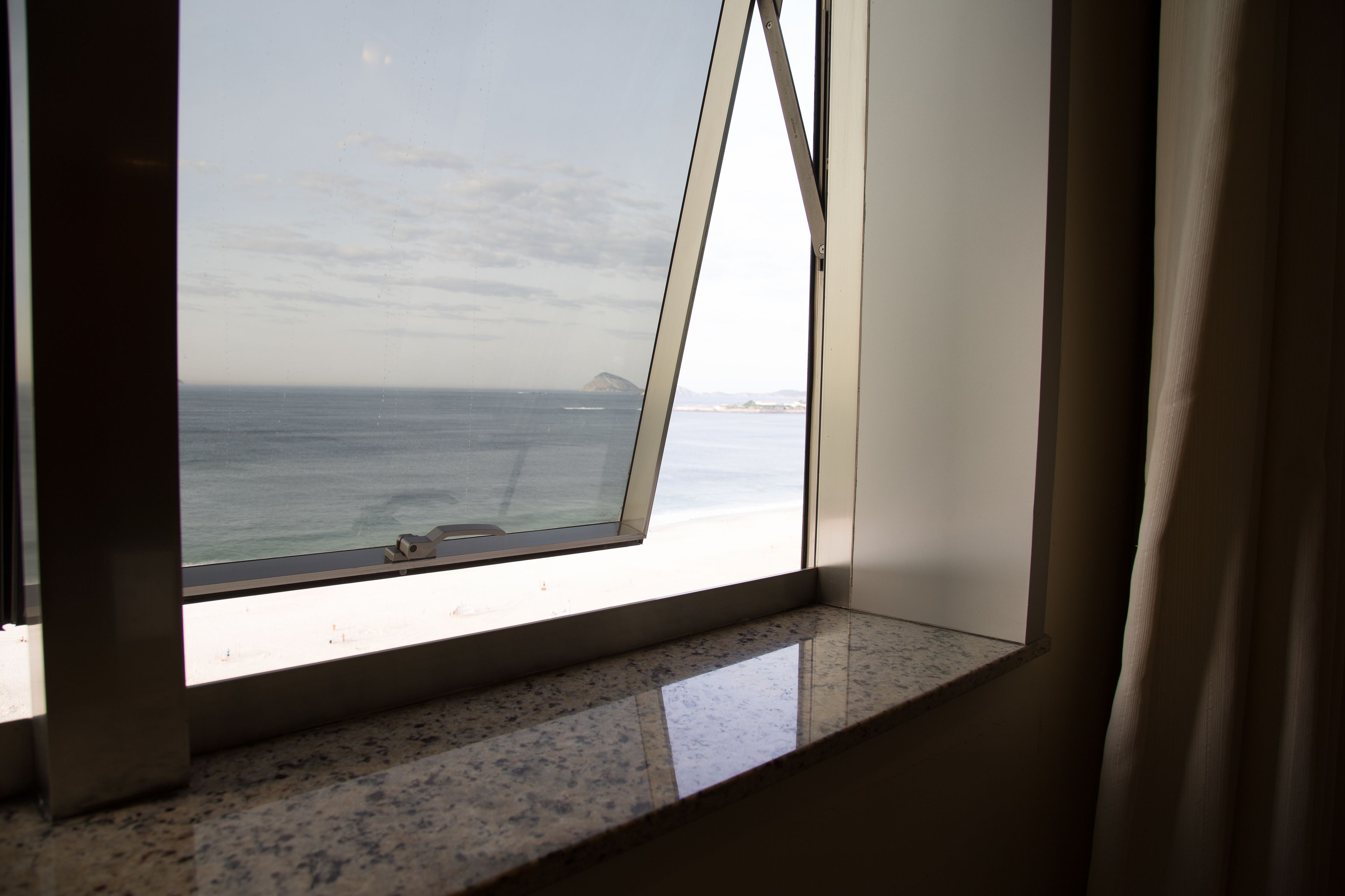 A window with a view of the sea and a distant island.