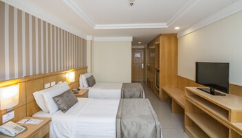A hotel room with two beds, a TV, a desk, and a phone.