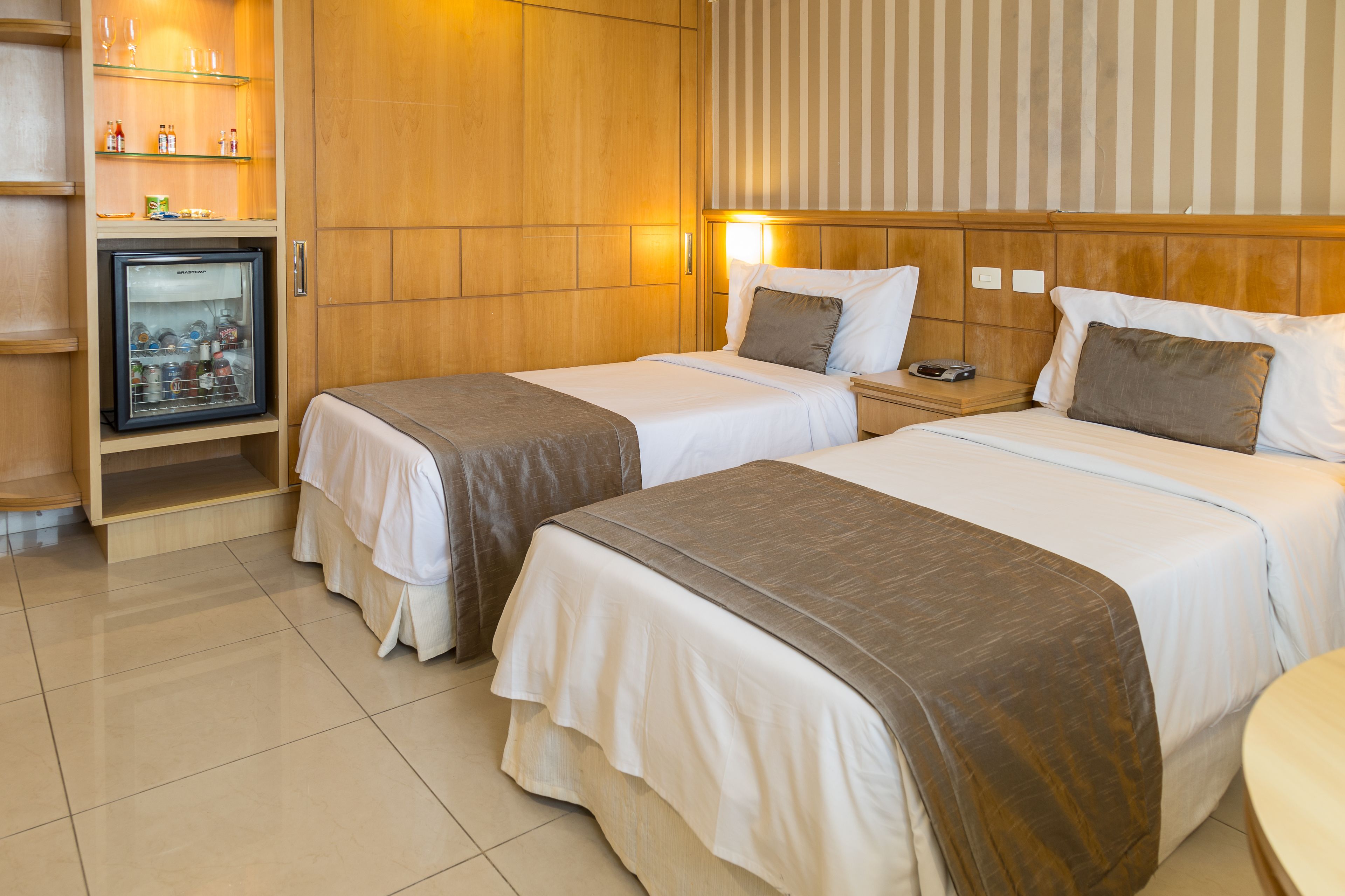 Habitación de hotel con dos camas, un minibar y televisión.