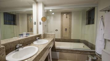 Une salle de bain avec deux lavabos, une baignoire et une douche séparée par une paroi en verre.