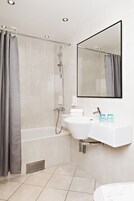 Un baño moderno con bañera, ducha y lavamanos dobles.