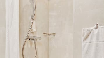 A modern bathroom with a shower, a towel rack, and a shower control panel.