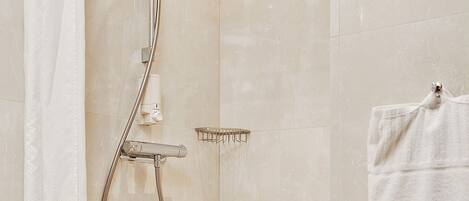 A modern bathroom with a shower, a towel rack, and a shower control panel.