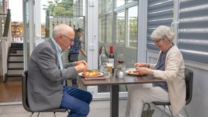 Comedor con una mesa dispuesta para dos personas, con una botella de vino, copas y platos de comida.