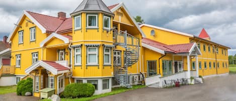 Un edificio amarillo con torreta y tejado rojo, que presenta una escalera y una pequeña zona de porche.