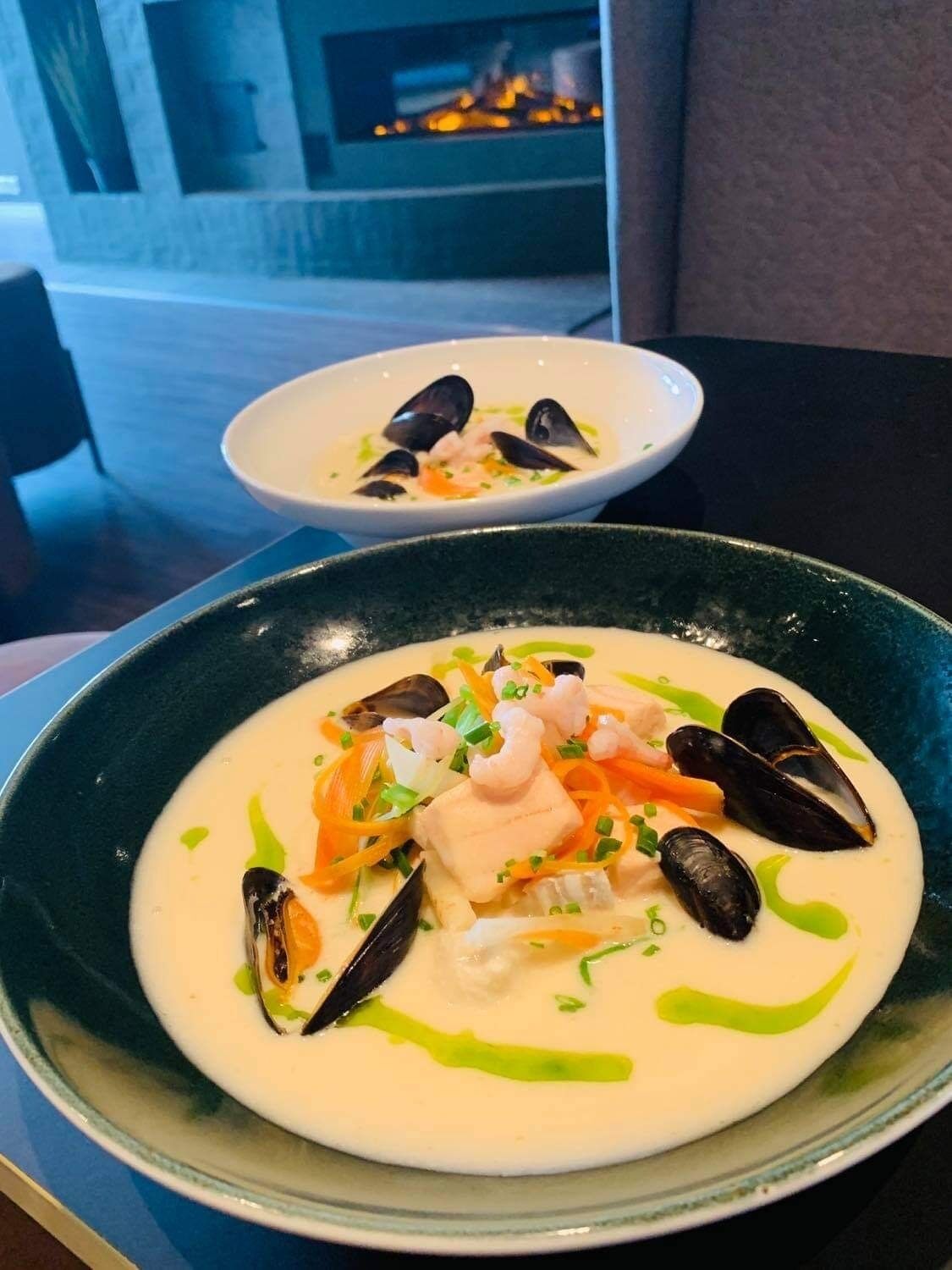 A seafood dish with mussels and shrimp on a creamy base, served in a green bowl.