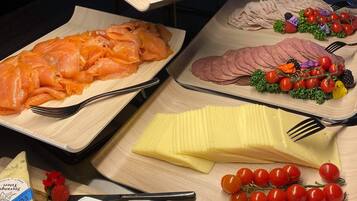 Un buffet proposant une variété de plats, notamment du saumon, du jambon, du fromage et des légumes frais.
