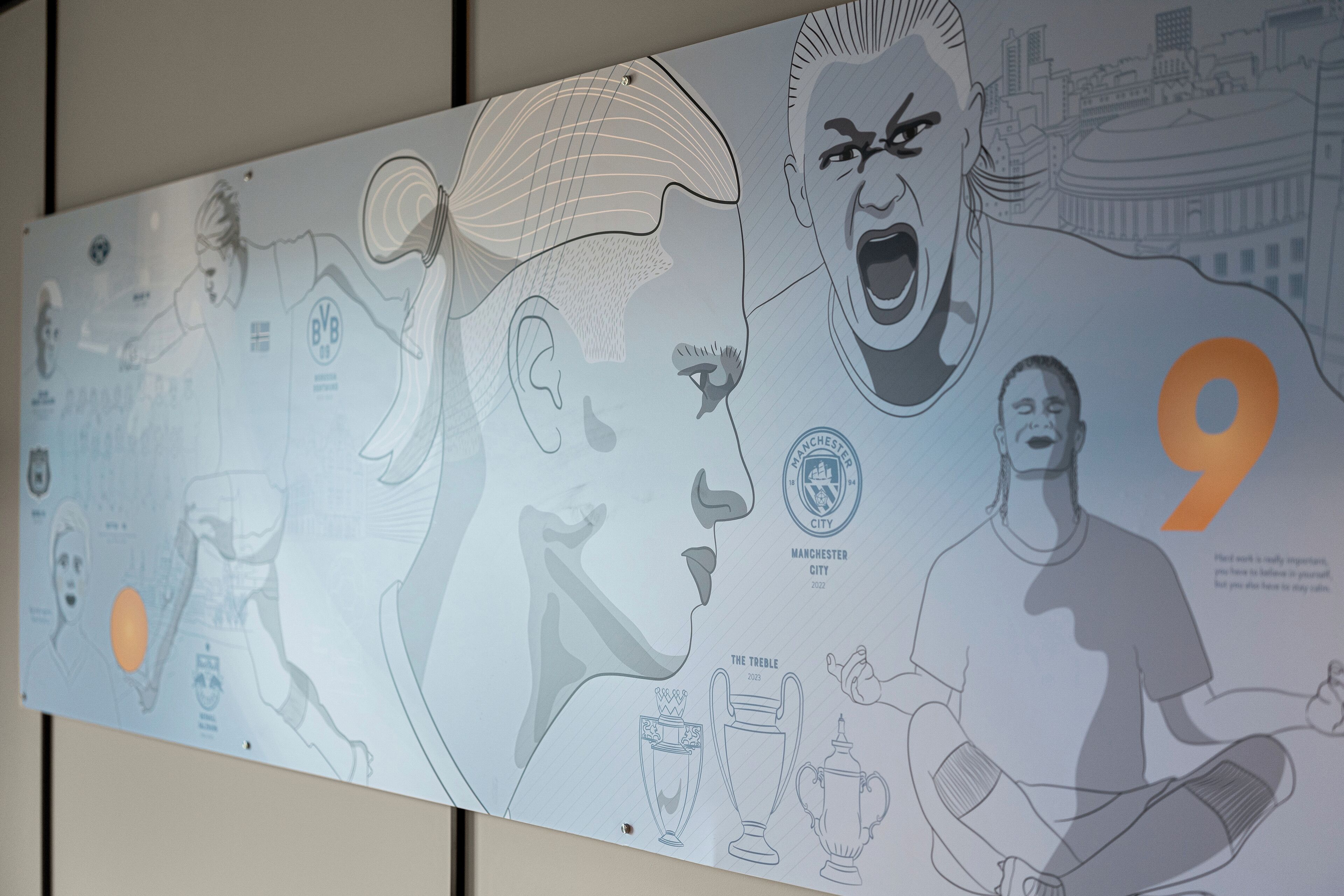 Pared con una ilustración detallada de un jugador de fútbol en acción, un trofeo y el número 9.
