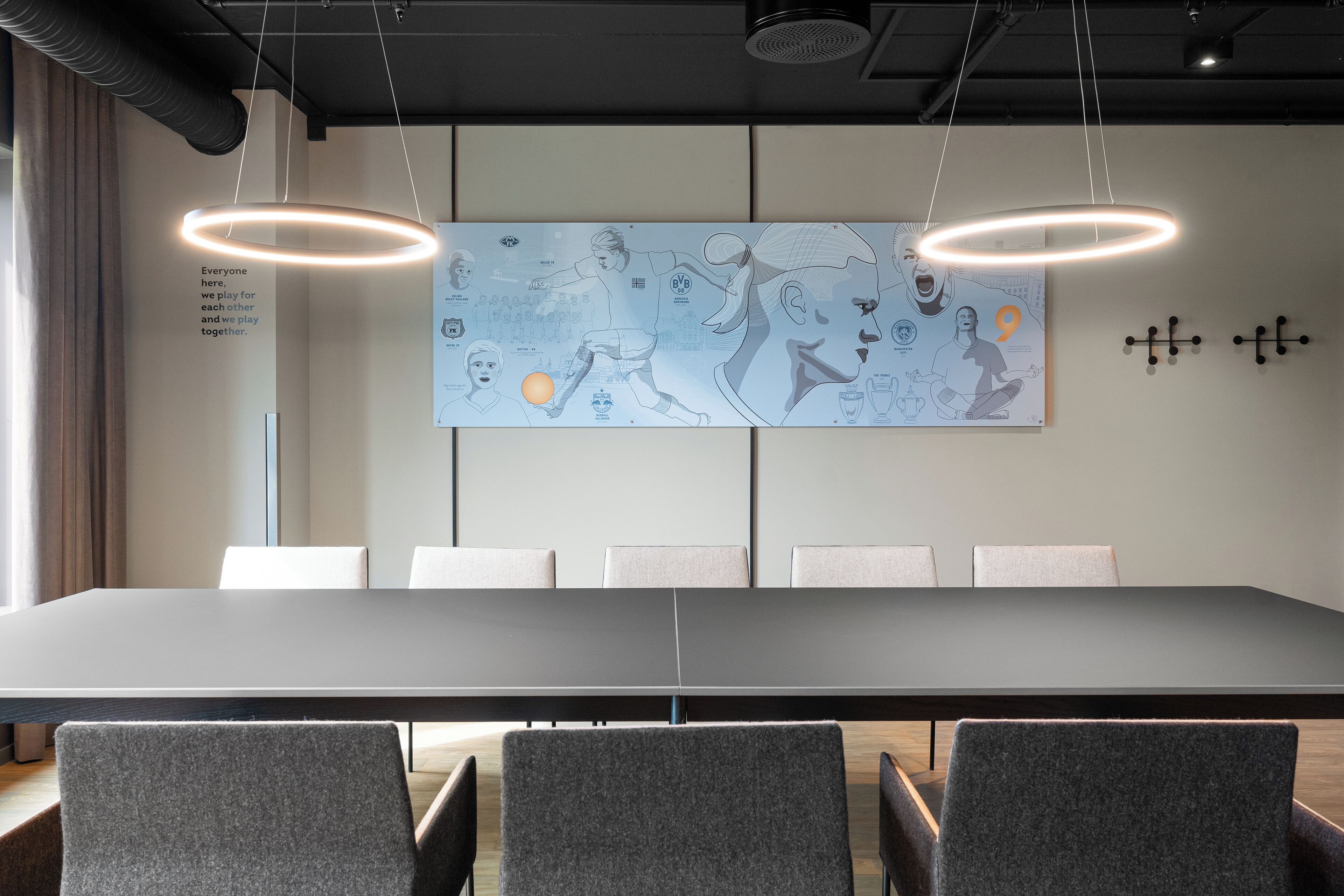 A conference room with a long table, six chairs, and a large abstract artwork on the wall.