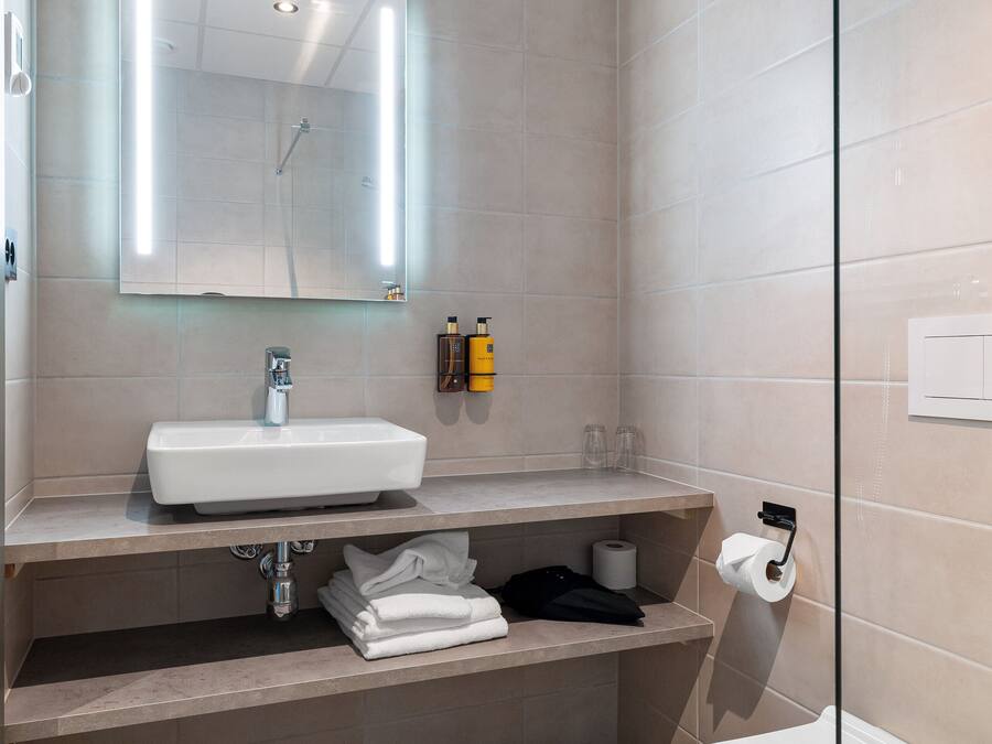 A modern bathroom with a glass-enclosed shower, a white sink, and a toilet.