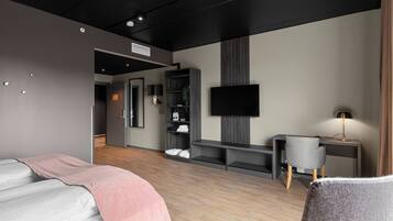 Una habitación de hotel moderna con cama, escritorio, televisión y armario.