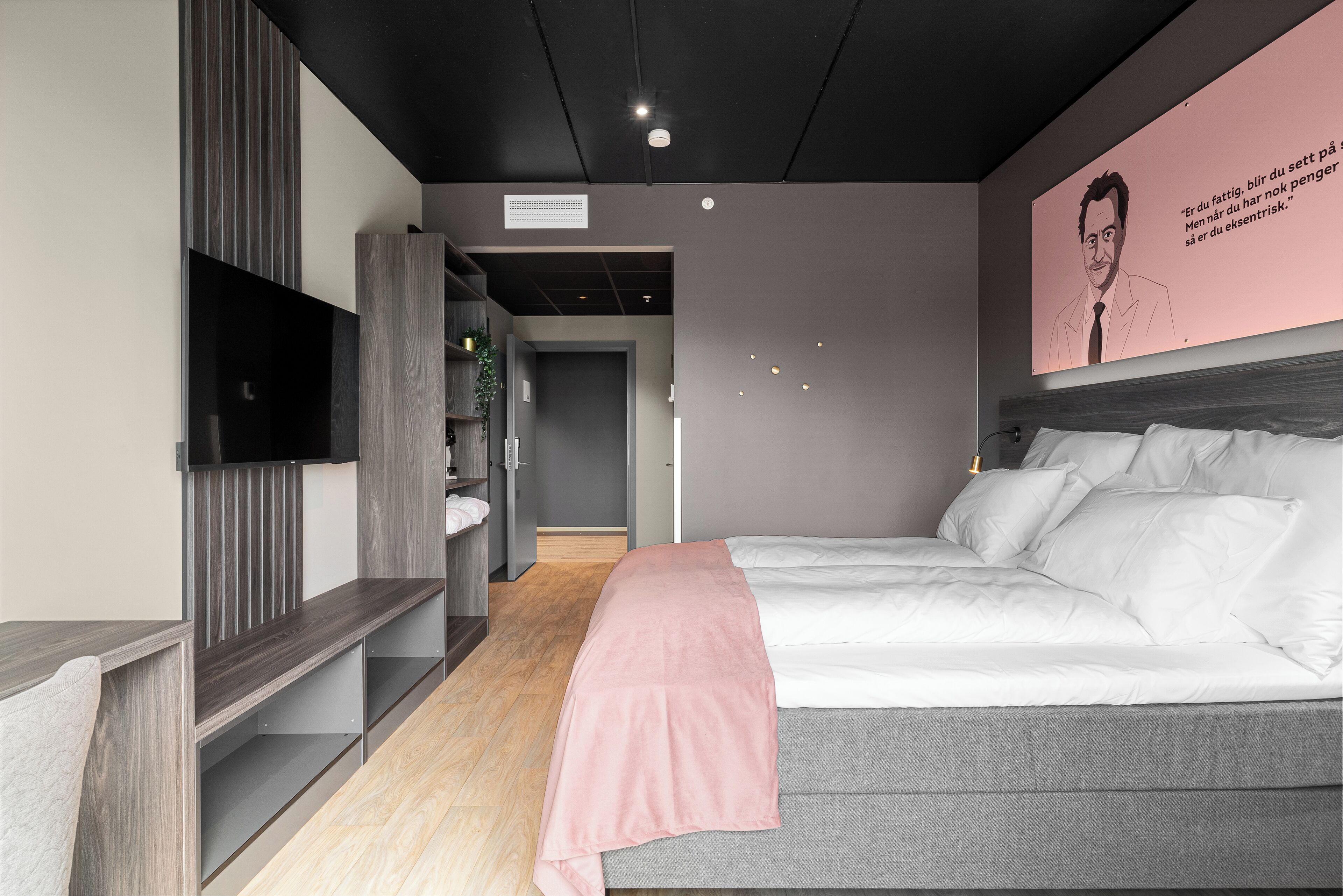 A modern bedroom with a bed, a TV, and a wall with a poster.