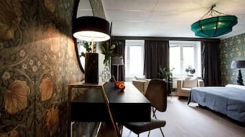 Habitación de hotel con mesa de comedor, sillas, cama y un amplio ventanal.