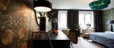 Habitación de hotel con mesa de comedor, sillas, cama y un amplio ventanal.