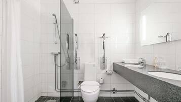 A modern bathroom with a glass-enclosed shower, a white toilet, and a granite countertop with a sink and mirror.